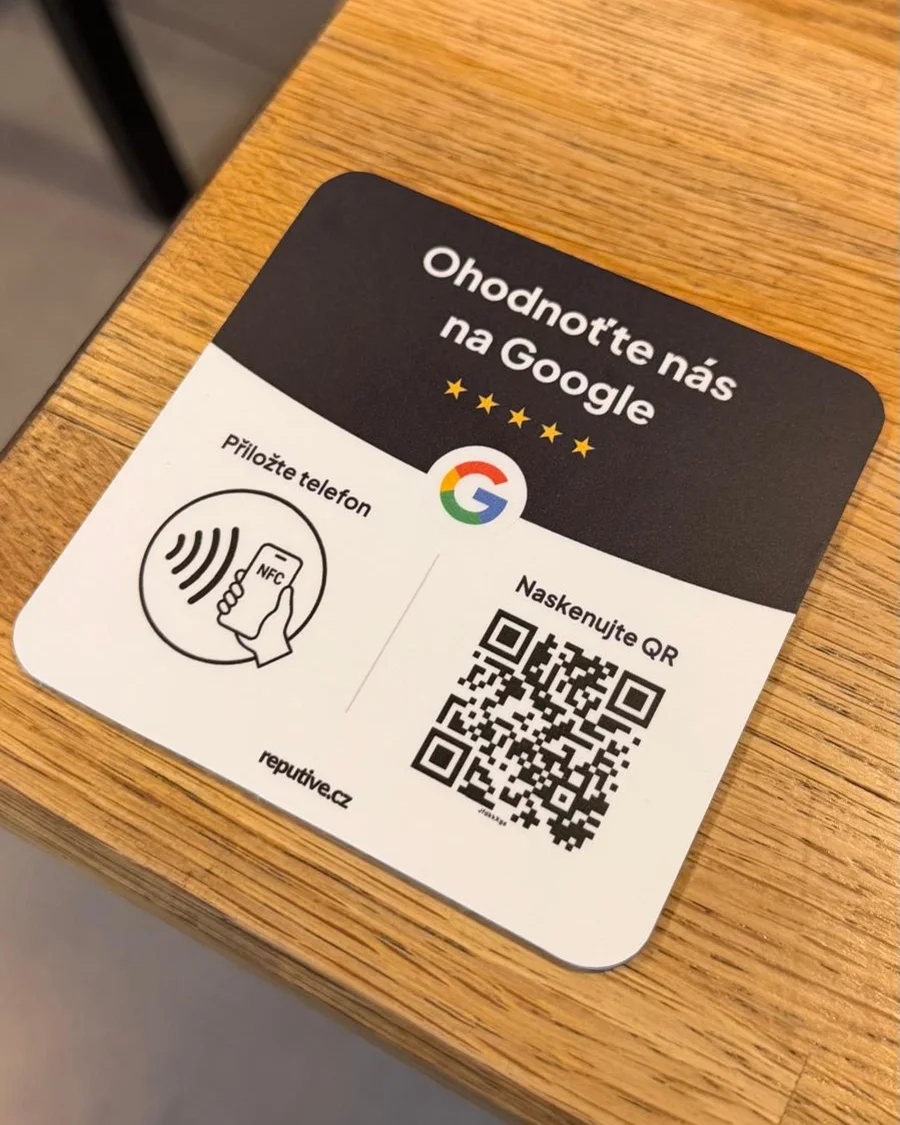 NFC destička na Google recenze položená na dřevěném stole v provozovně